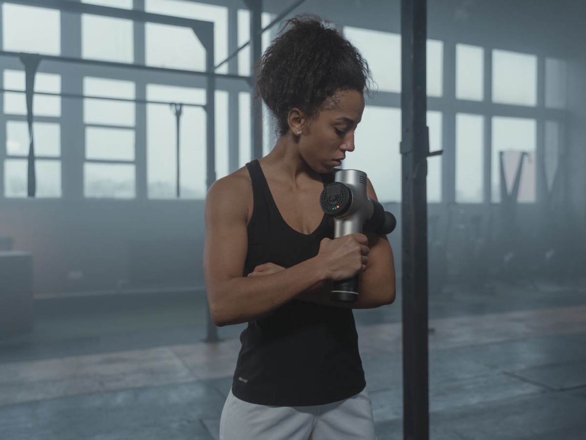 Sportive utilisant un massage gun après sa séance