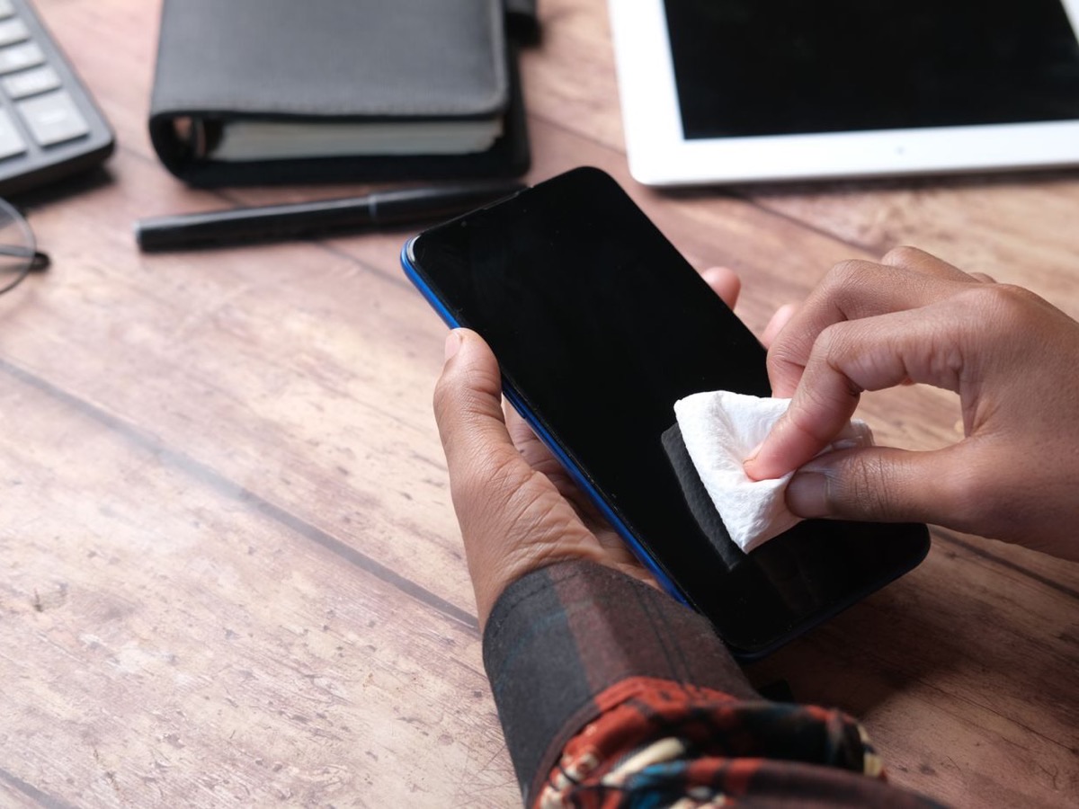 Mains nettoyant un téléphone avec un chiffon